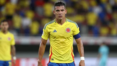 Mid-30s Colombian forward, athletic build, waist-up shot, intense gaze toward camera, wearing Colombia home kit - bright...