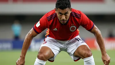 A photorealistic image of an anonymous Colombian player in their home kit, with the player's face visible and their eyes...