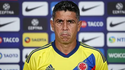 A close-up shot of a 35-year-old, ruggedly-built, Colombian national team assistant coach, with a stern expression...