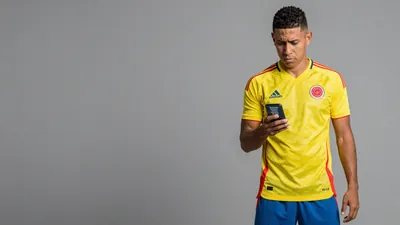 A photorealistic image of a Colombia player, wearing a yellow jersey and blue shorts, with a concerned expression...