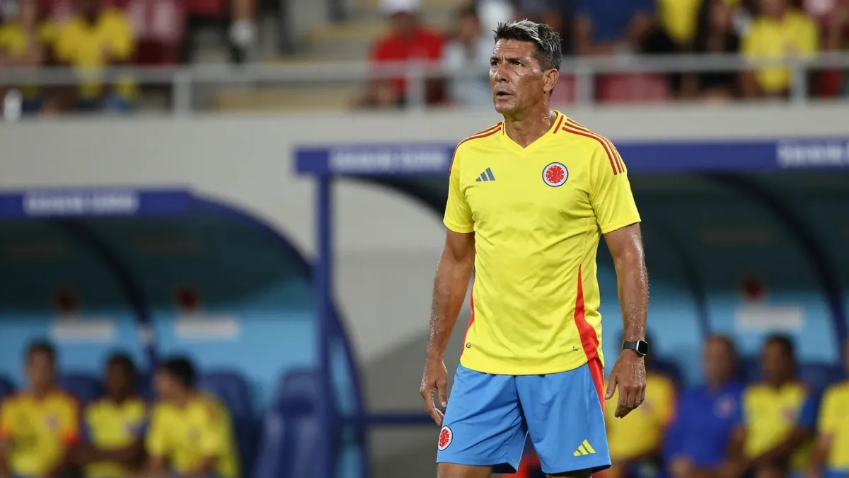 A 35-year-old Colombian national team coach, wearing the Colombia home kit with a bright yellow shirt and sky blue...