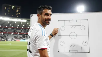 A photograph of Rafa Márquez, a 47-year-old defender, standing in front of a whiteboard with a diagram of a football...