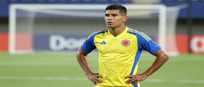 A muscular Colombian national team player in his mid-20s, wearing a plain yellow and blue training top with clean fabric...
