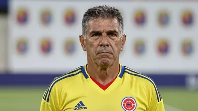 A close-up shot of a middle-aged, 5'9" Colombian coach with a weathered face and a stern expression, dressed in the...