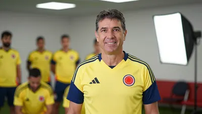 A 55-year-old coach with a kind face, wearing a Colombia national team jersey, standing in the center of the frame, with...