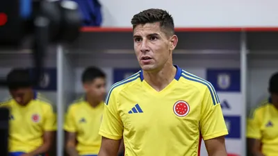 A 30-year-old male Colombian national team player in yellow and blue home kit, mid-conversation with a serious...