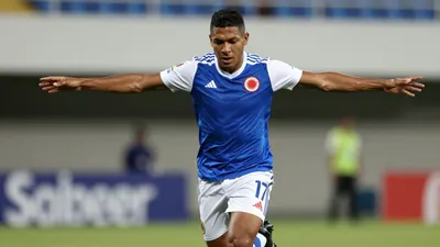 A tight action crop of an anonymous Colombian football player in his mid-20s, wearing a blue jersey with white sleeves...