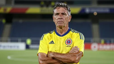 A 50-year-old Colombian coach with a rugged build, wearing the yellow and blue home kit of Los Cafeteros, with the...