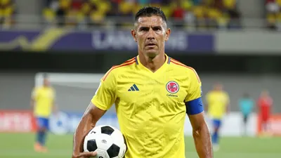 A muscular Colombian midfielder in his late 30s, wearing the Colombia national team's yellow and blue home kit with the...
