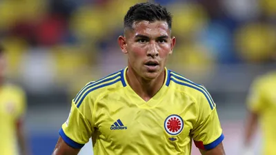Mid-shot of a determined 24-year-old Colombian midfielder, muscular build, face flushed with focus, wearing the yellow...